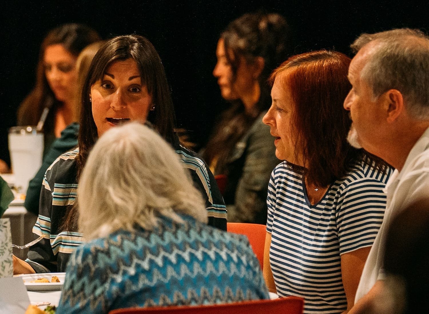 Adults sharing a conversation around a table.